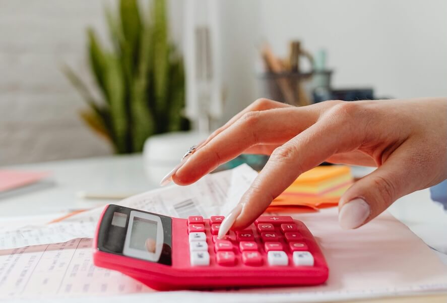 The hand of a person typing on a calculator to signify planning and budgeting in local government.