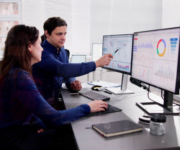 Local government employees discussing impactful metrics on a performance analytics software presented on two monitors