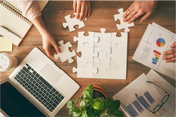 Image of public sector leaders using a strategy execution software on their laptop, while building a puzzle and looking at hard copy charts.
