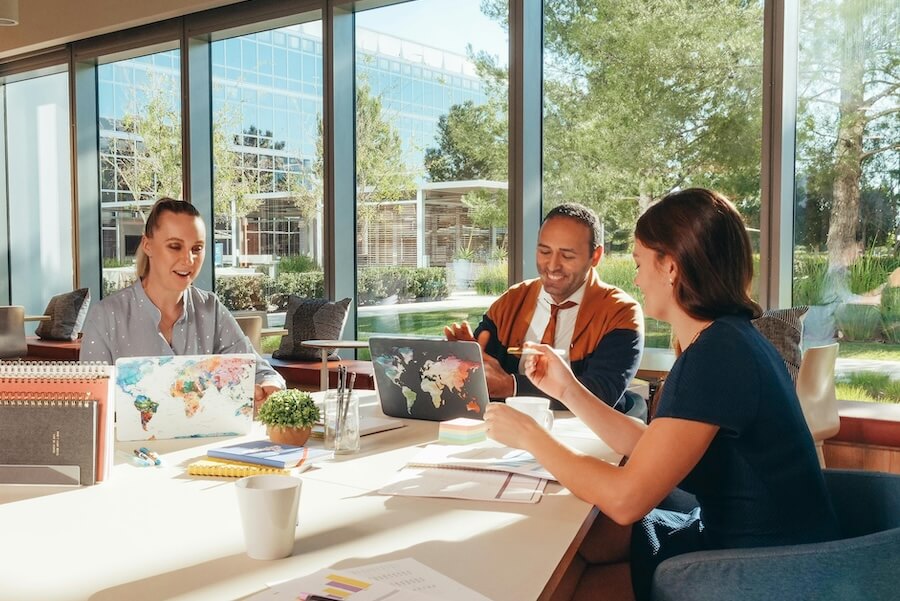 Photo of three people laughing around a table.
