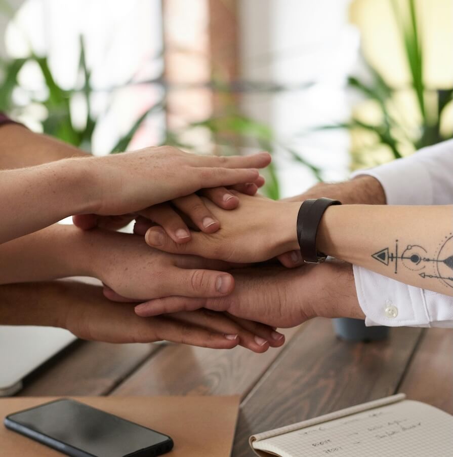 Photo of hands piled up on top of each other at the start of an action planning workshop.