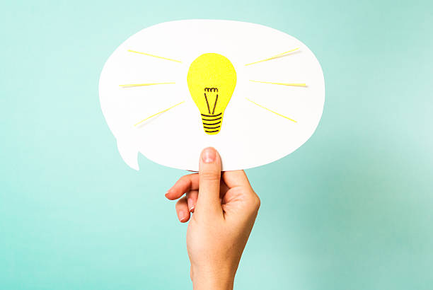 Hand holding cardboard speech bubble with light bulb drawn on