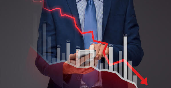 Photo of a man in a suit holding a chart showing a downward trend