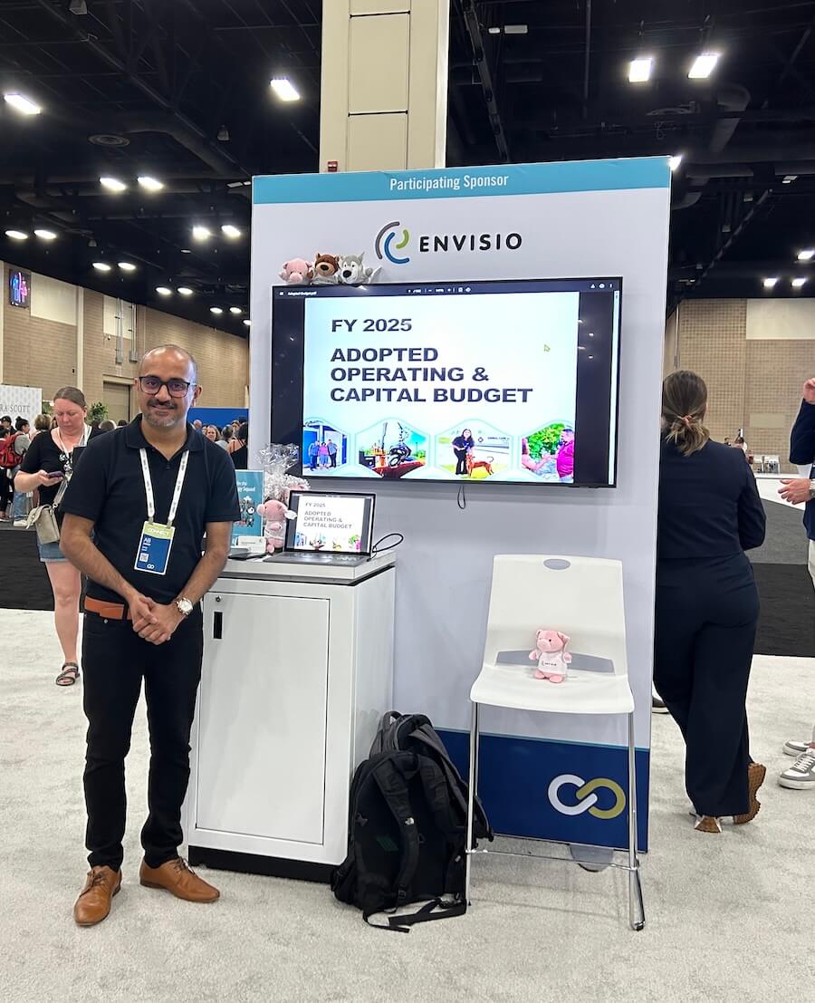 Photo of an Envisio booth when a member of staff standing in front.