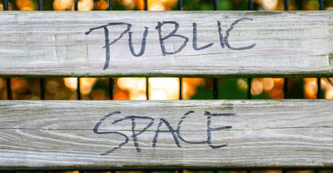 Image of a bench with the words "public space" written on in black pen.