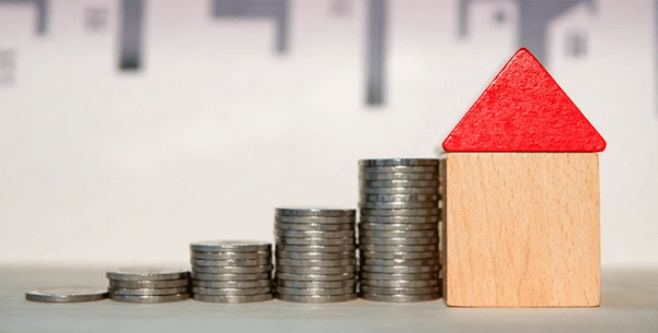 Photo of coins stacked up against a wooden block house