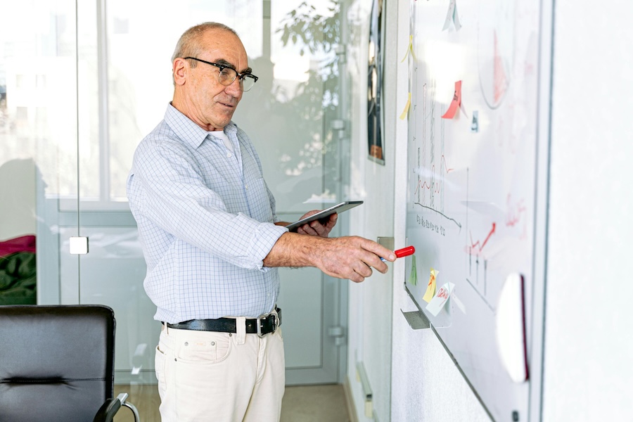 Government leader reviewing strategic planning dashboard on tablet and whiteboard