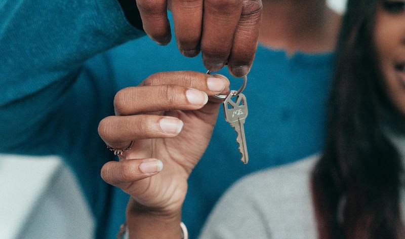 a close up of a person holding a set of house keys, handing them to another person