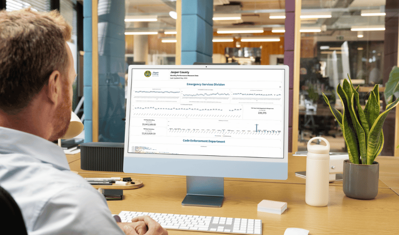 a man looking at a computer screen showing an Envisio powered performance analytics dashboard